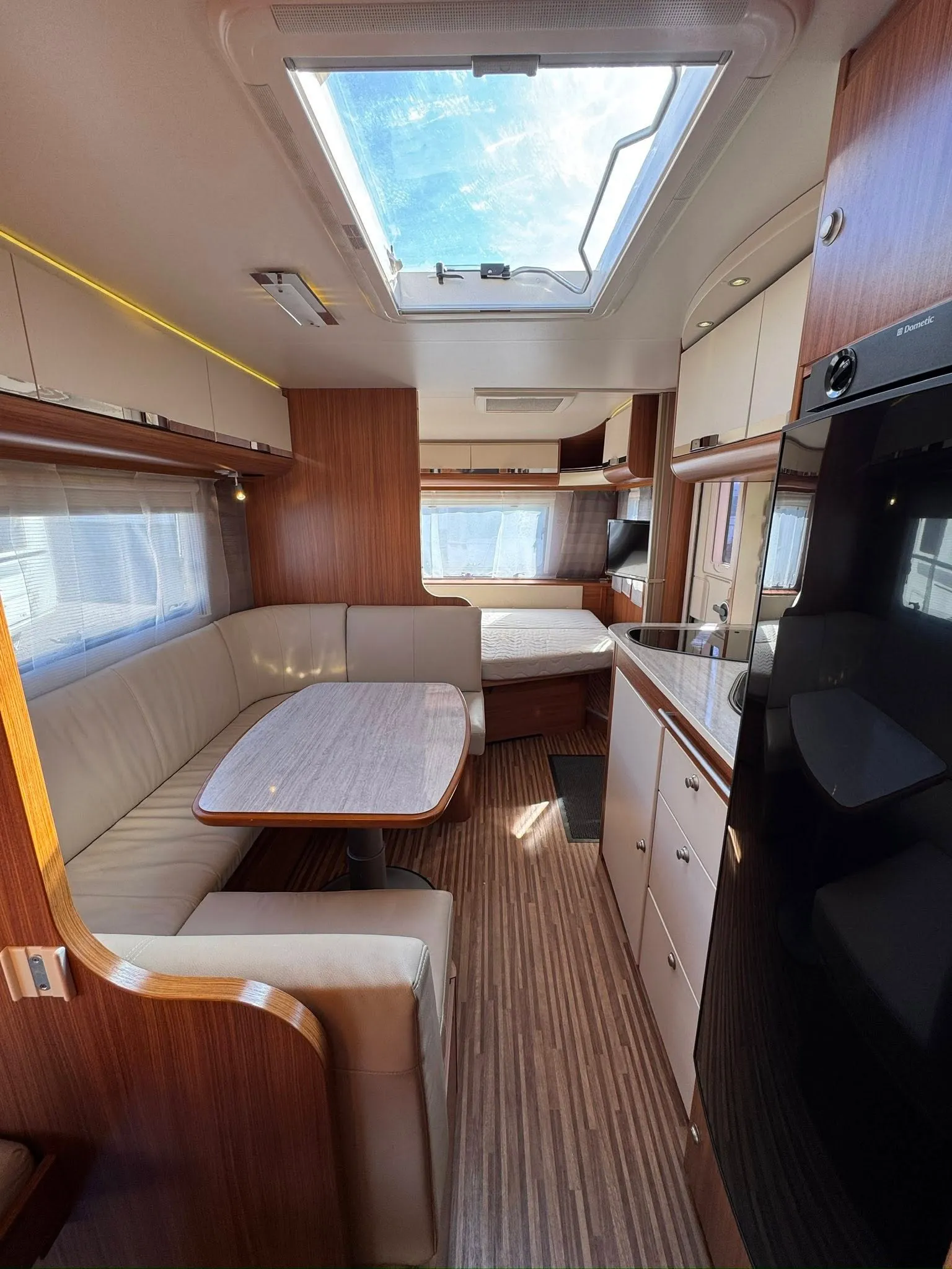 Interiér karavanu s pohodlným sezením a kuchyňkou, ideální pro cestování a relaxaci.