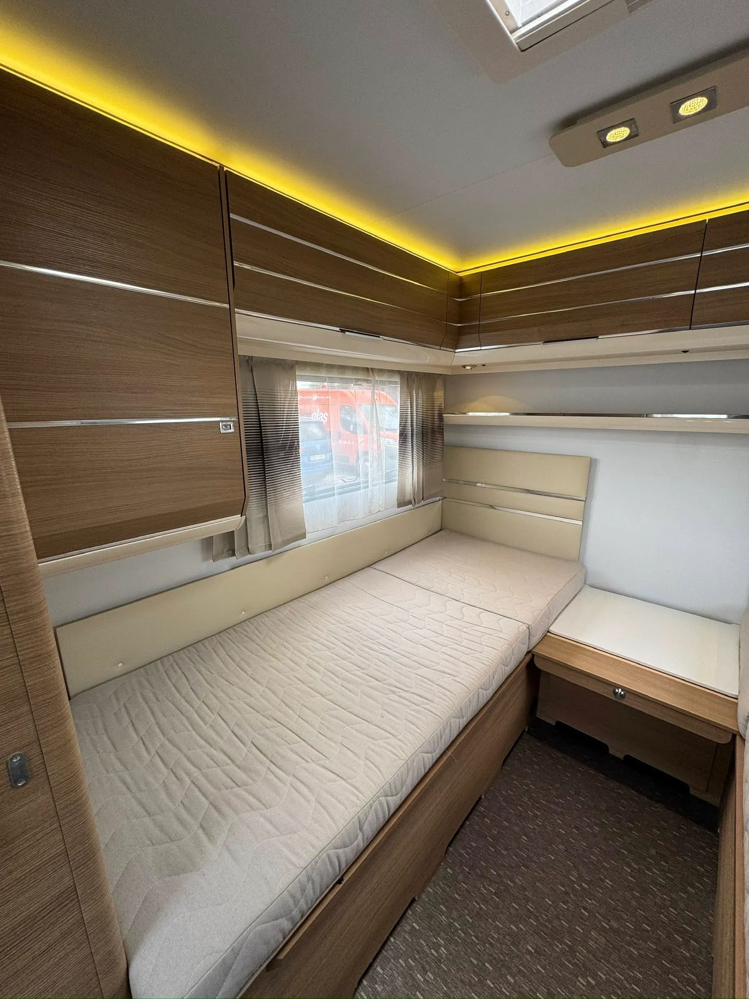 Interiér karavanu s pohodlným lůžkem a moderním designem. Ideální pro relaxaci na cestách.