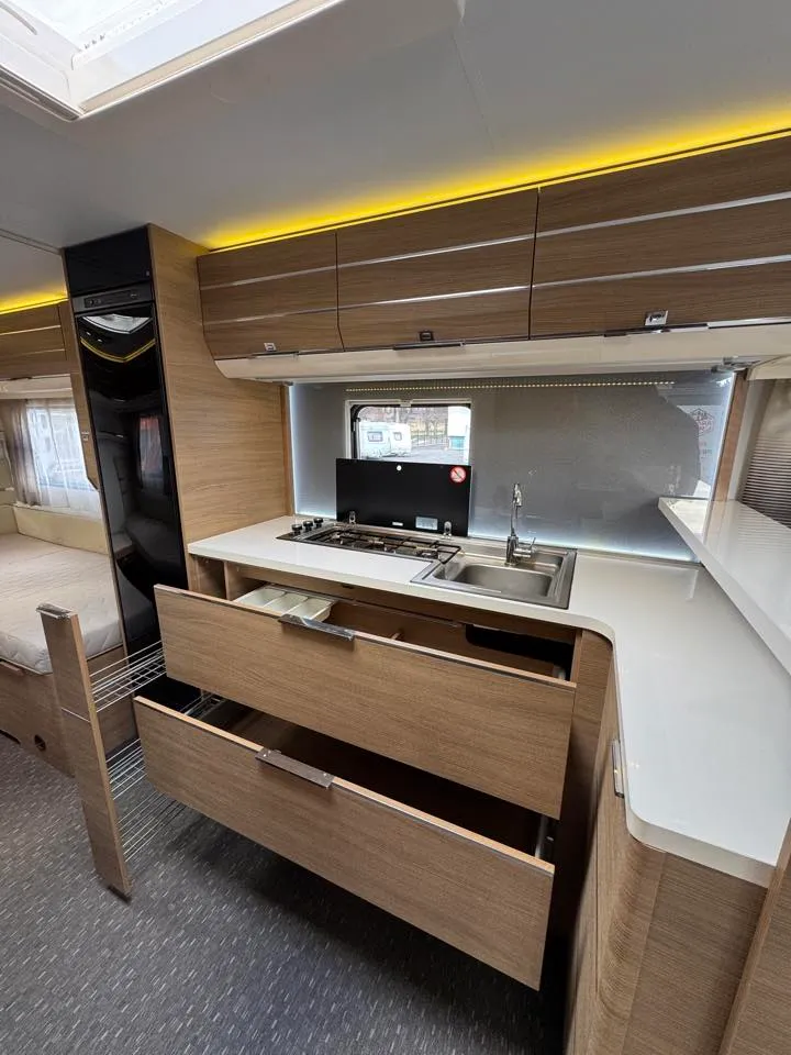 Moderní interiér s kuchyňským koutem v obytném autě. Praktické úložné prostory a elegantní design.