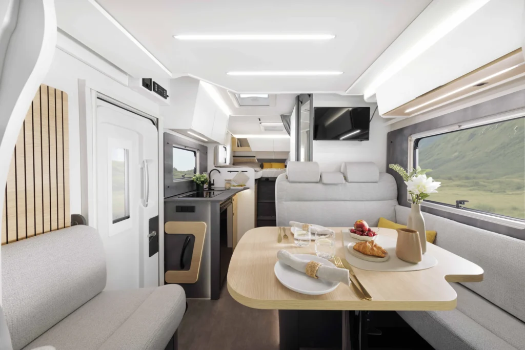 Interiér obytného auta s moderním designem, kuchyň a pohodlné posezení. Ideální pro pohodlné cestování a relaxaci.