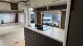 Interiér karavanu s moderním kuchyňským koutem a pohodlným spací prostorem pro nevšední zážitky na cestách.
