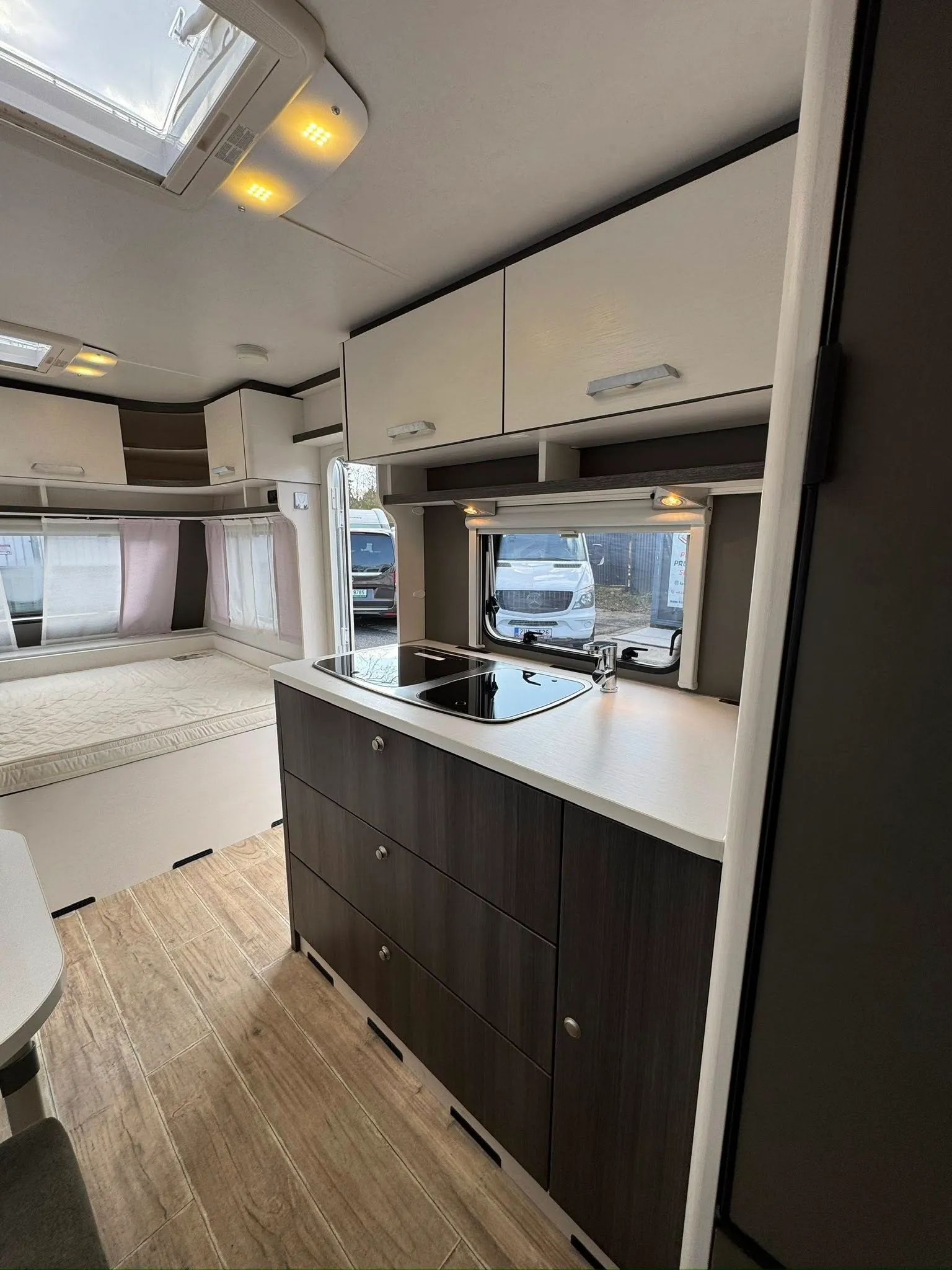 Interiér karavanu s moderním kuchyňským koutem a pohodlným spací prostorem pro nevšední zážitky na cestách.