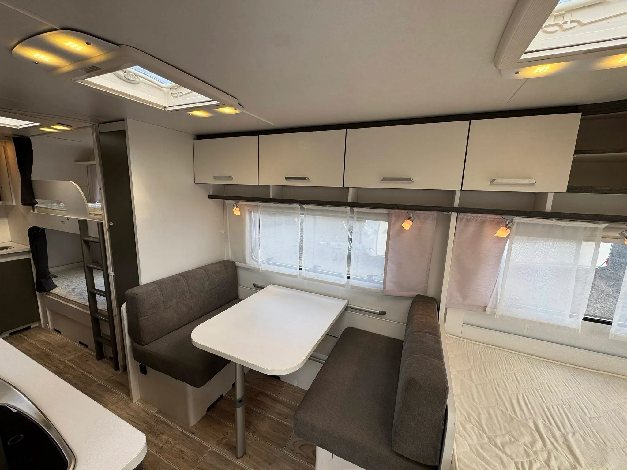 Interiér karavanu s pohodlným sezením, stolkem a praktickým osvětlením. Ideální pro rodinné dobrodružství.