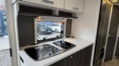 Obrázek interiéru obytného vozu, moderní kuchyňka s dřezem a úložnými prostory. Stylový design pro pohodlí.