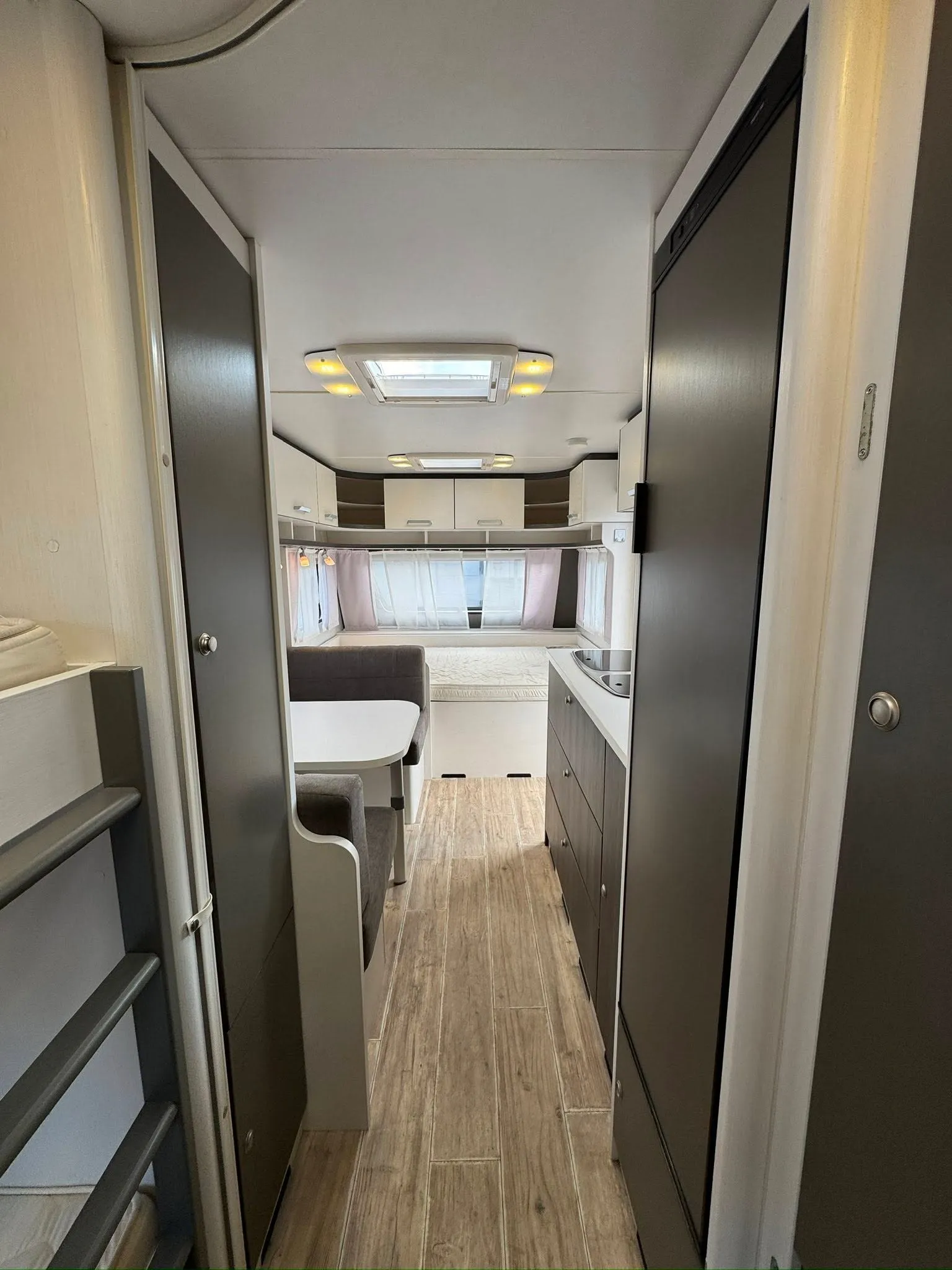 Interiér karavanu s moderním designem a prostorným uspořádáním, ideální pro pohodlné cestování.