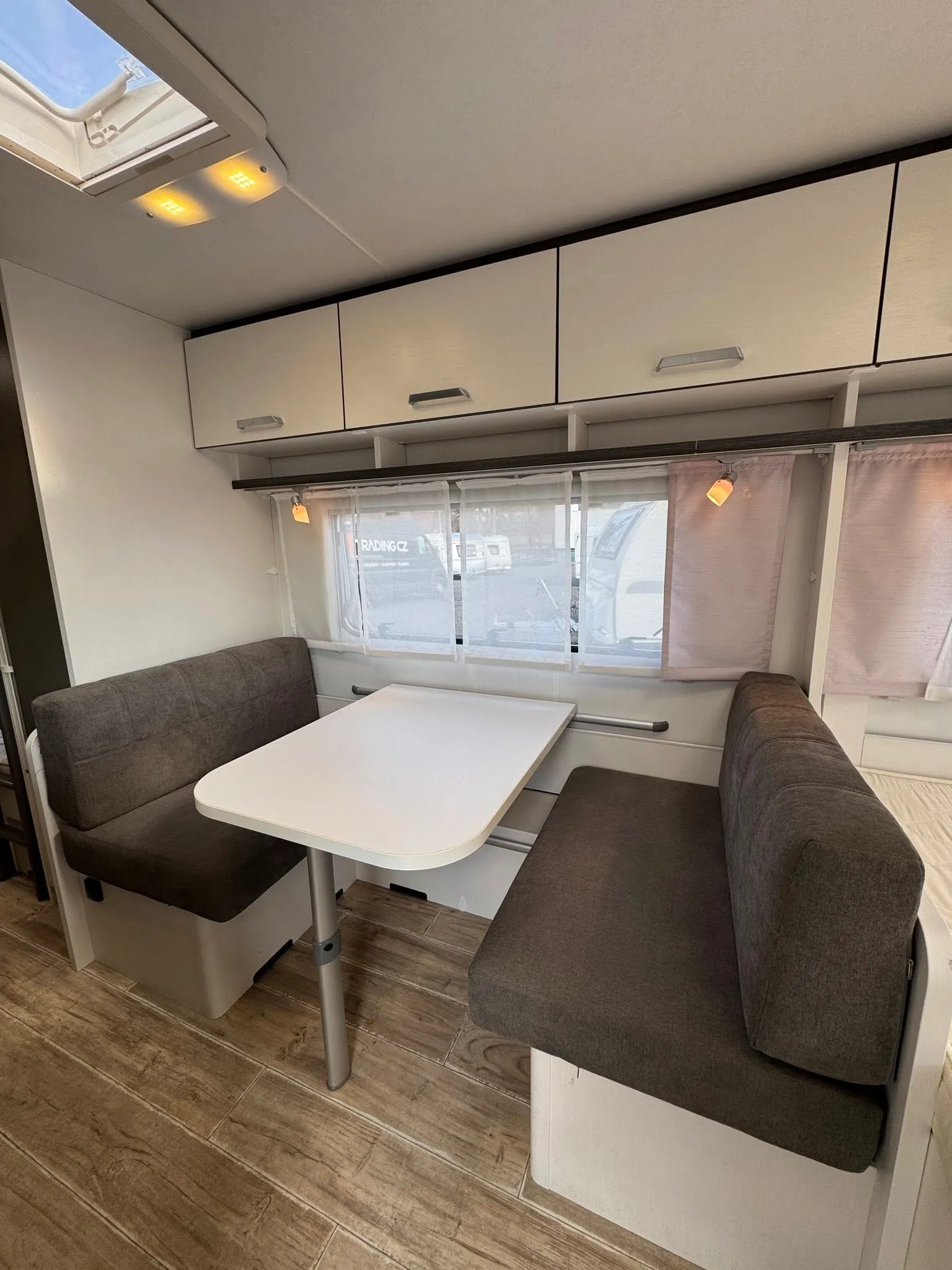 Obrázek interiéru obytného vozu s pohodlným sezením a stolem. Skvělé místo pro relaxaci na cestách!