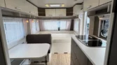 Interiér karavanu s moderním designem, kuchyňskou linkou a pohodlným sezením. Ideální pro dovolenou.
