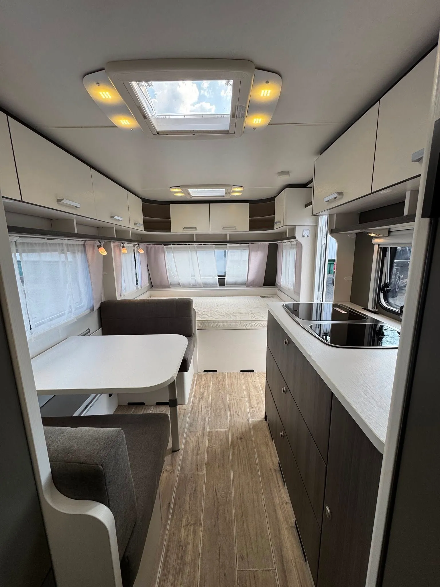 Interiér karavanu s moderním designem, kuchyňskou linkou a pohodlným sezením. Ideální pro dovolenou.