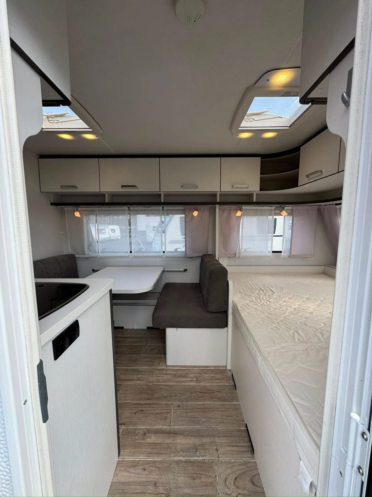 Interiér karavanu, moderní design, pohodlné posezení a spací prostor. Ideální pro dobrodružství na cestách.