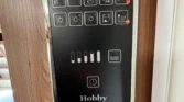 Ovladač systému v karavanu Hobby, dobře přehledný a moderní design pro pohodlné užívání.