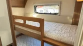 Obrázek ukazuje interiér karavanu s patrovou postelí. Moderní a praktické řešení pro rodinné využití.