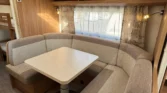 Interiér karavanu s pohodlným sezením a stolkem. Moderní design a útulná atmosféra pro relaxaci.
