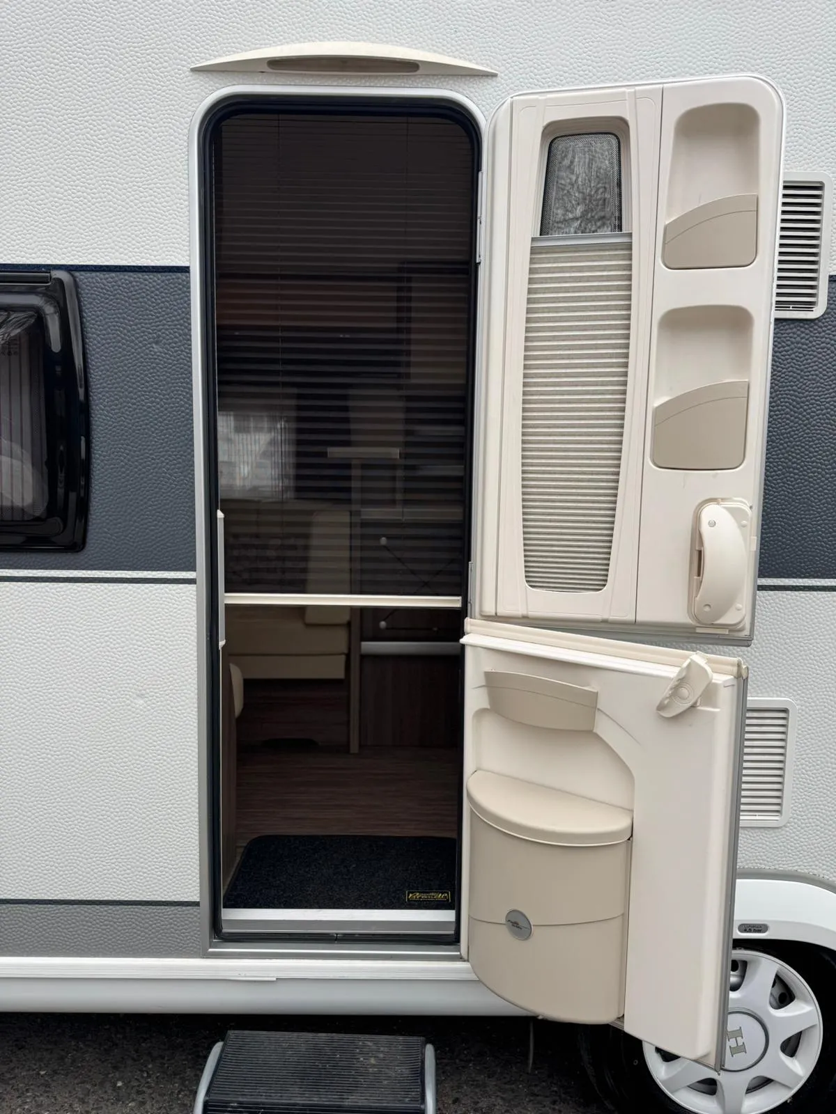 Obrázek zobrazuje vchod do karavanu s moderním designem a praktickými detaily.