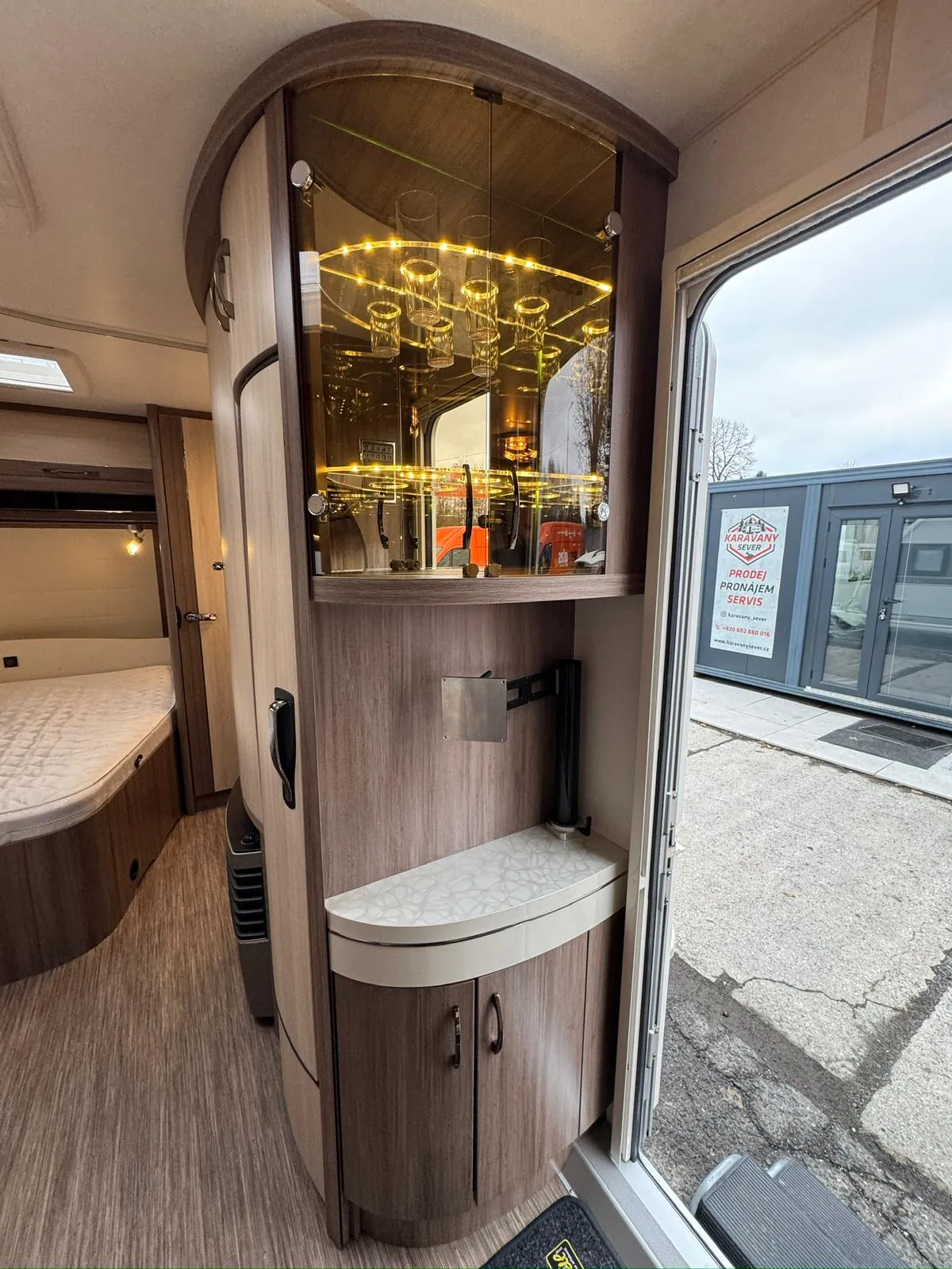 Interiér moderního obytného auta s elegantním vitrínovým systémem a praktickými úložnými prostory.