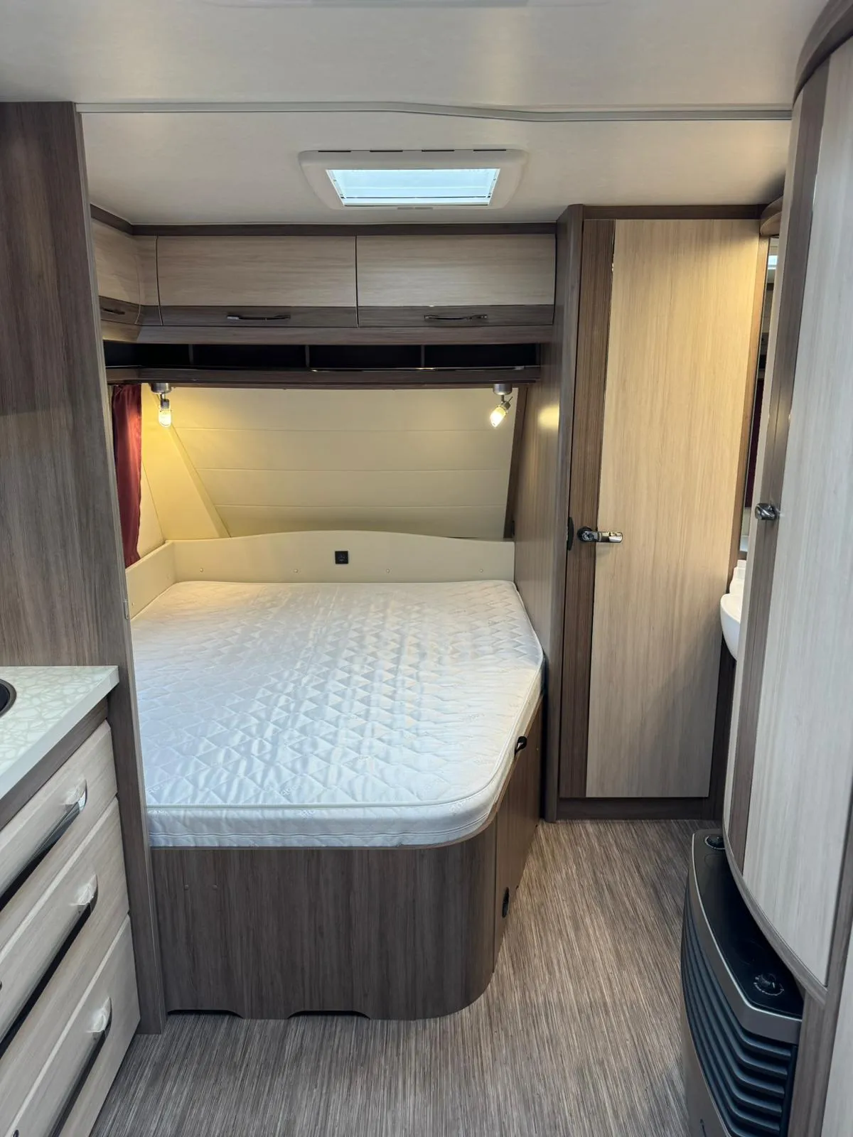 Toto je interiér karavanu s manželskou postelí a moderním designem. Vhodný pro pohodlné cestování.