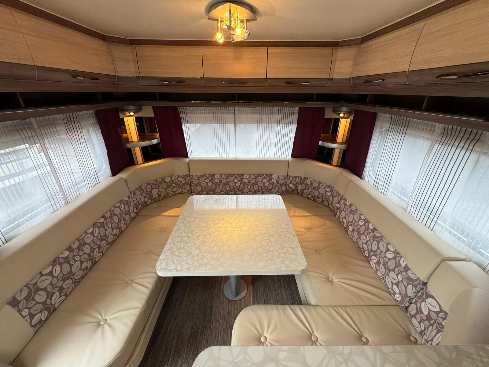 Interiér karavanu s prostorným sezením a stolkem, ideální pro pohodlné cestování a odpočinek.