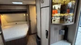 Interiér obytného vozu, moderní a útulný, s pohodlnou postelí a dostatkem úložného prostoru. Ideální pro dobrodružství.