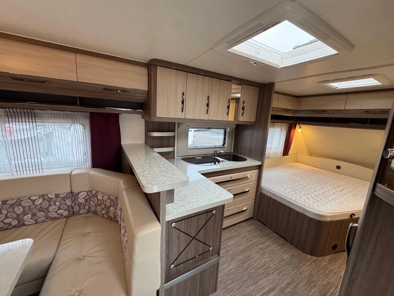 Interiér karavanu s moderním designem a pohodlným vybavením. Prostor zahrnuje kuchyni a ložnici.