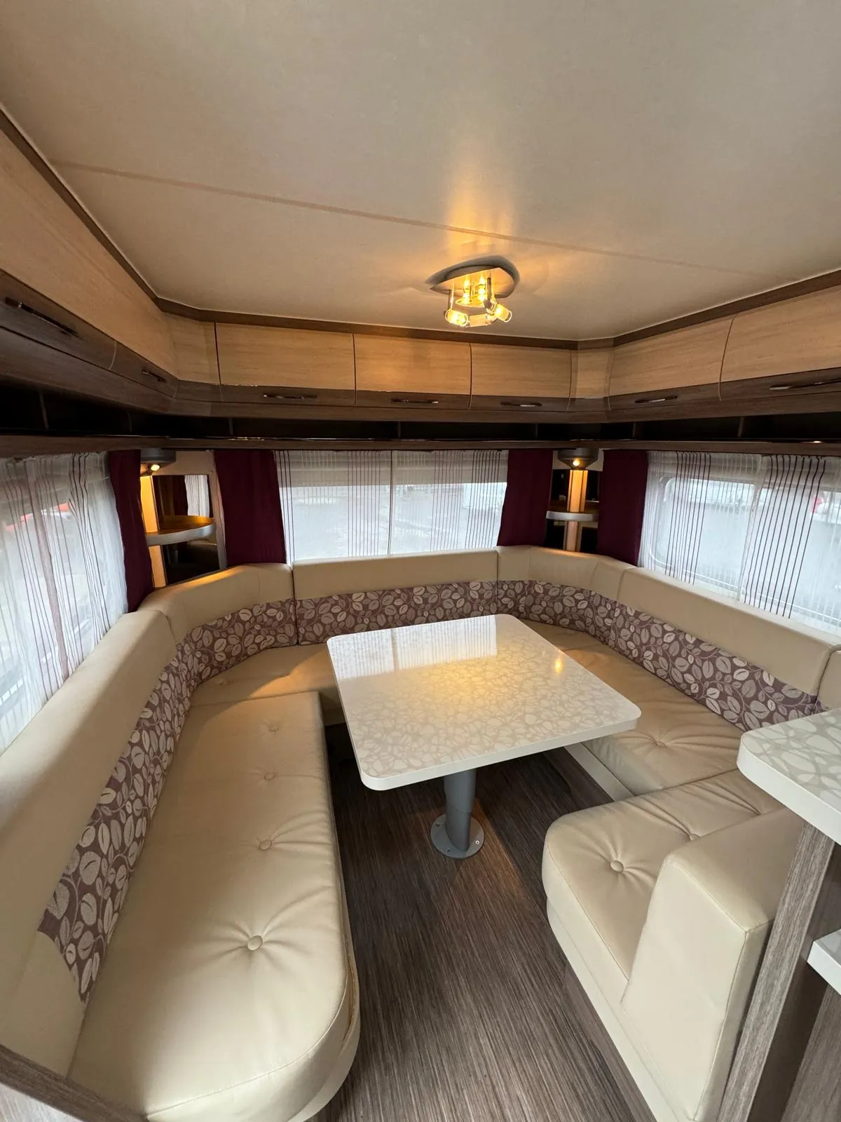 Interiér karavanu s prostorným sezením a stolkem, ideální pro pohodové víkendové výlety.
