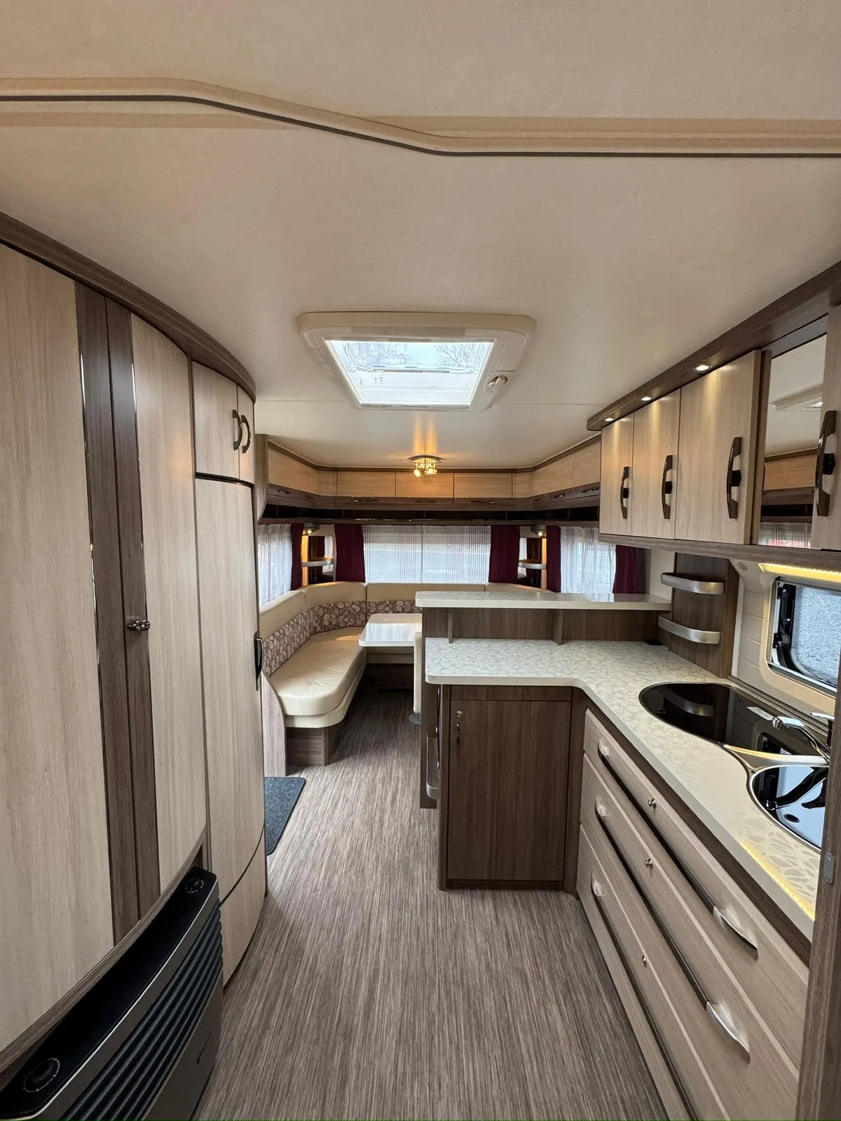 Obrázek interiéru karavanu s moderním designem, dřevěnými prvky a kuchyňským koutem. Ideální pro pohodlné cestování.