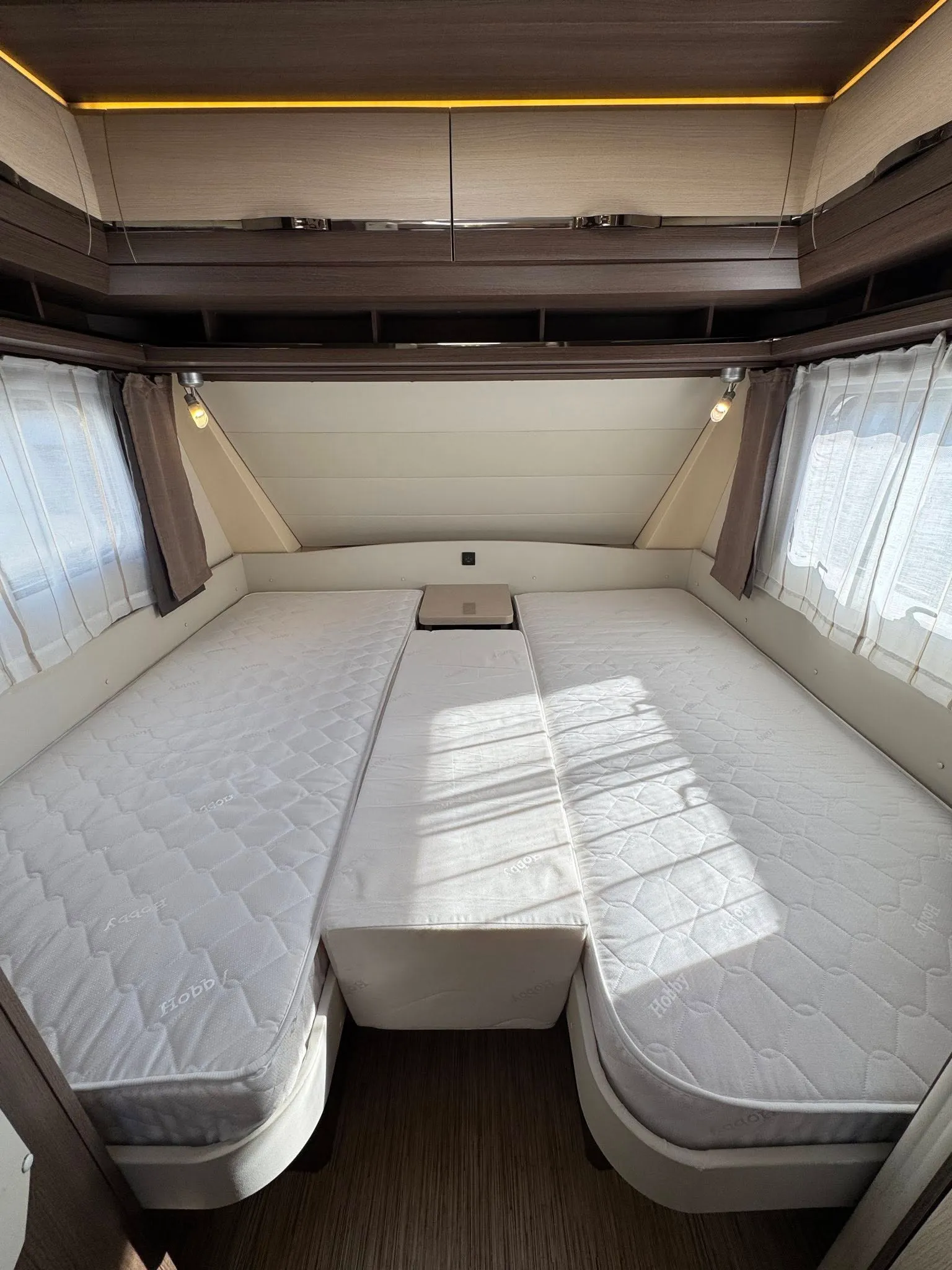 Interiér karavanu s prostorným lůžkem a příjemným osvětlením. Model: Hobby.