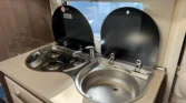 Kuchyňka obytného auta s dvouplotýnkovým vařičem a dřezem. Moderní design pro pohodlné vaření na cestách.