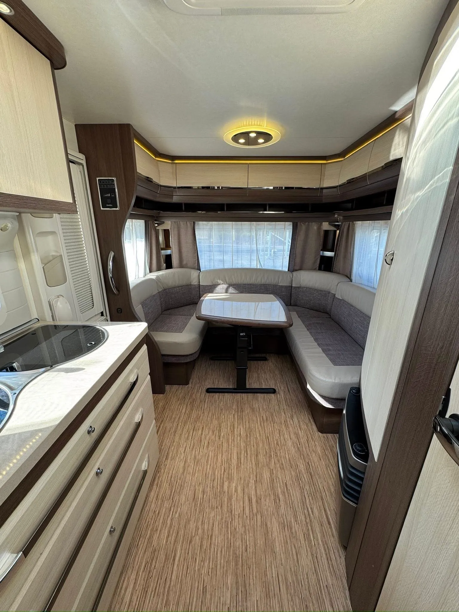 Obrázek interiéru karavanu s moderním designem a komfortním posezením. Elegantní a prostorný pro relaxaci.