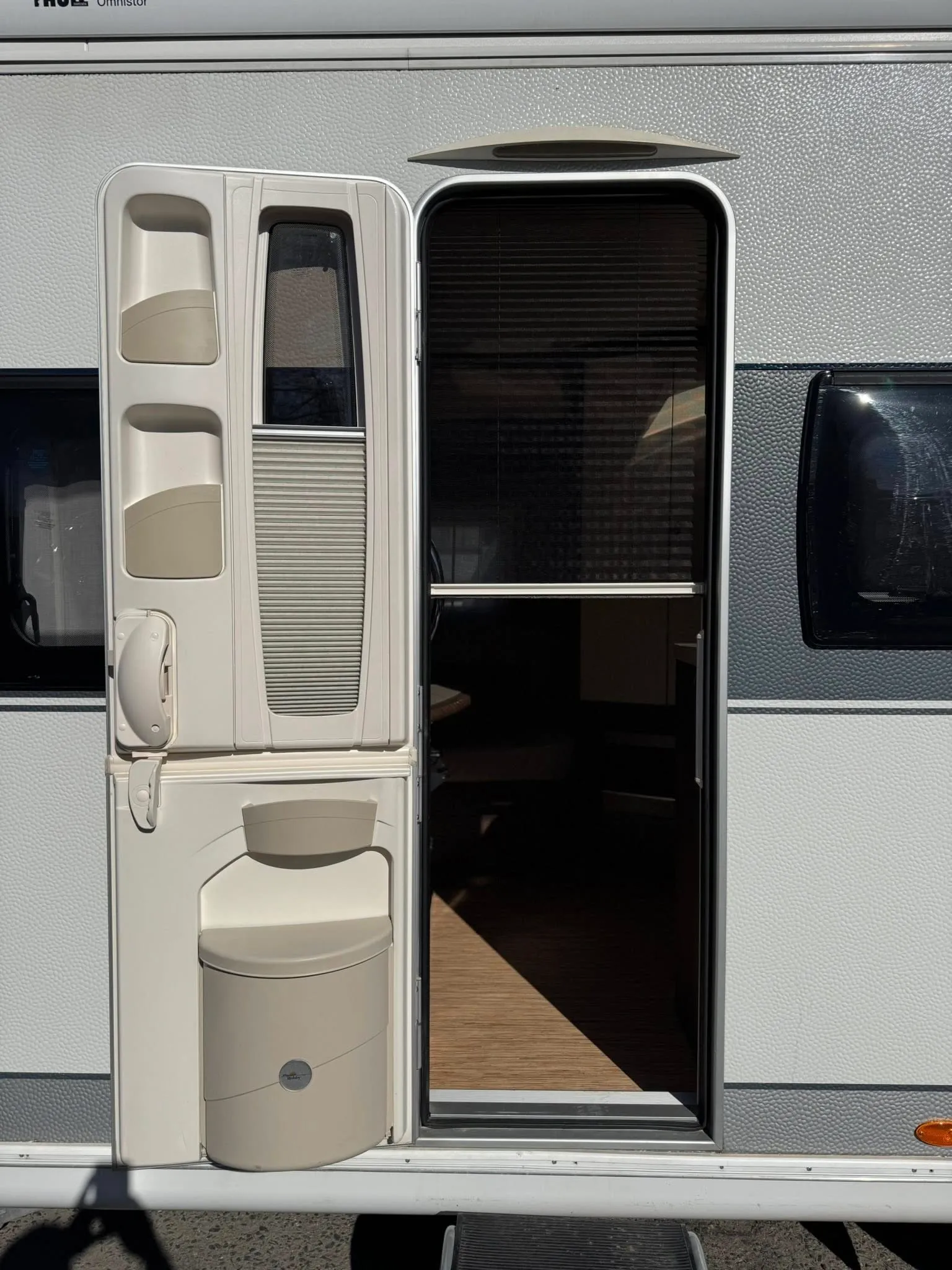 Obrázek ukazuje vchod do karavanu s moderním designem a praktickými doplňky.