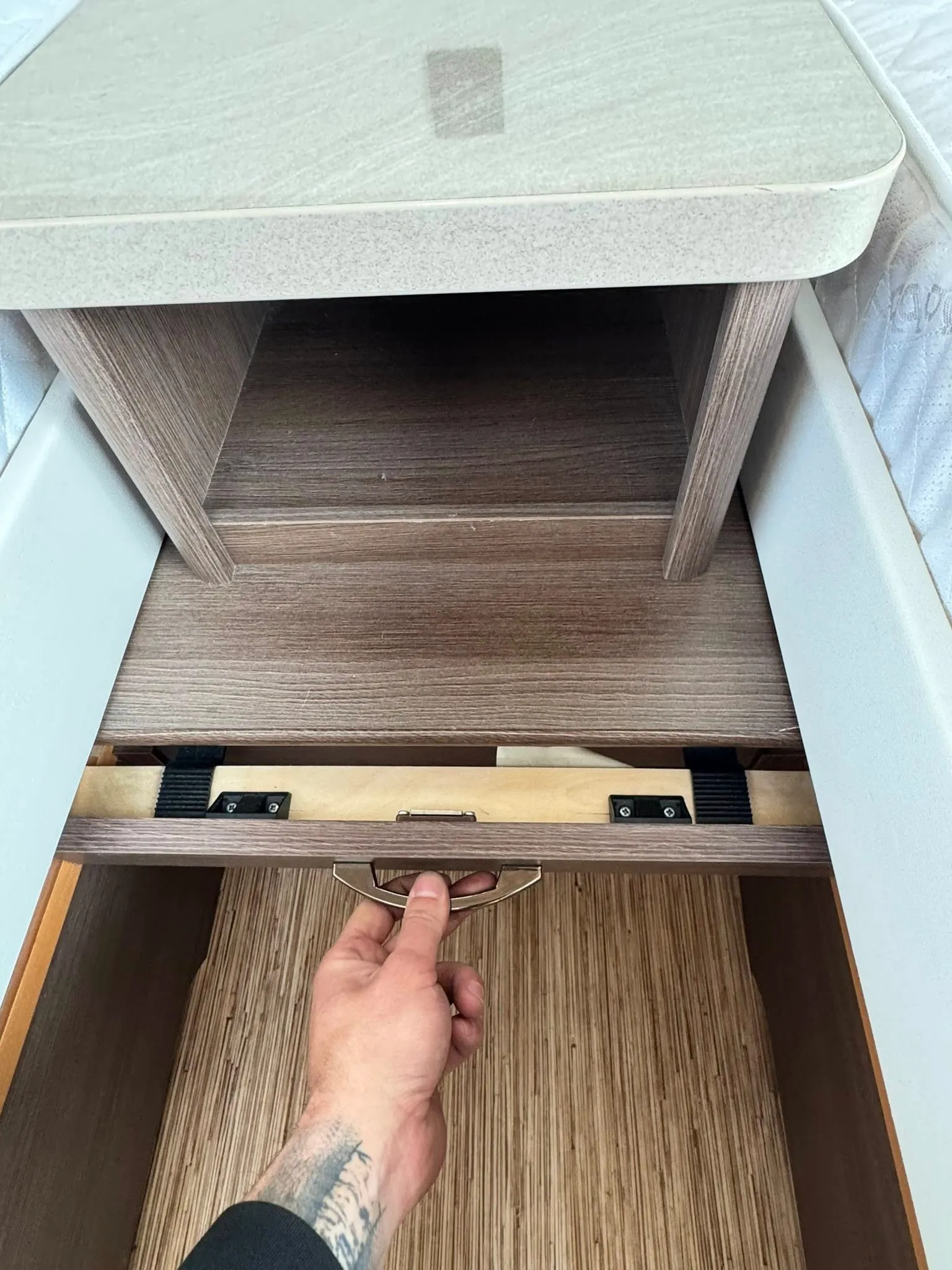 Obrázek ukazuje úložný prostor ve zvýšeném lůžku obytného auta s moderním designem a praktickým úchytem.