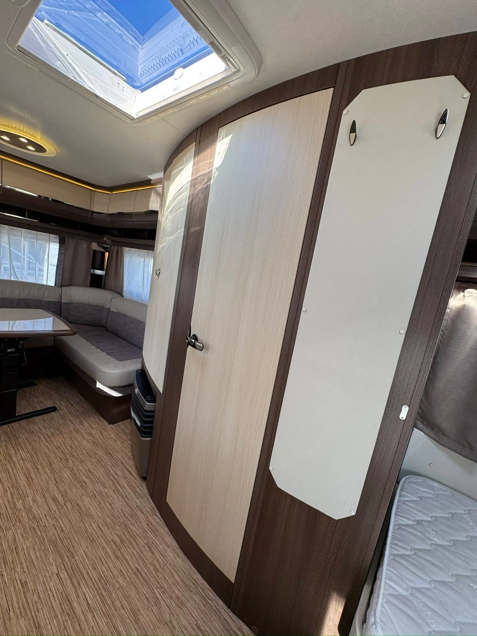 Interiér karavanu s prostorným sezením a střešním oknem, elegantní design a moderní vybavení.