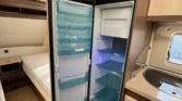Obrázek interiéru karavanu s moderním lednicí a prostornými úložnými skříněmi. Vhodné pro pohodlné cestování.