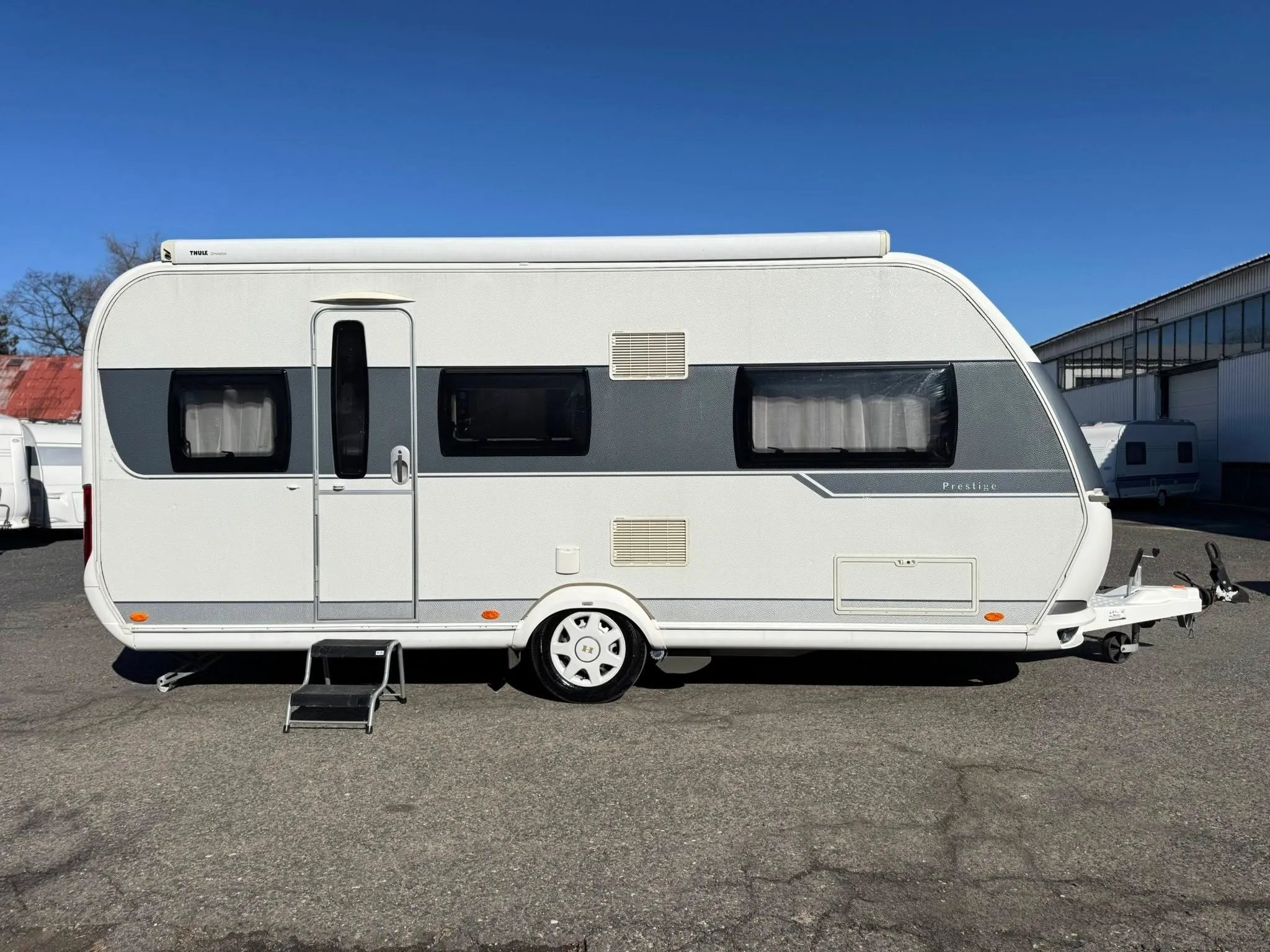 Karavan Prestige, bílá barva, s velkými okny a stahovací stříškou, ideální pro dovolenou.