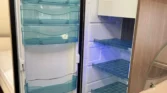 Obrázek zobrazuje lednici v obytném autě. Vnitřní prostor je dobře uspořádán s průhlednými přihrádkami.