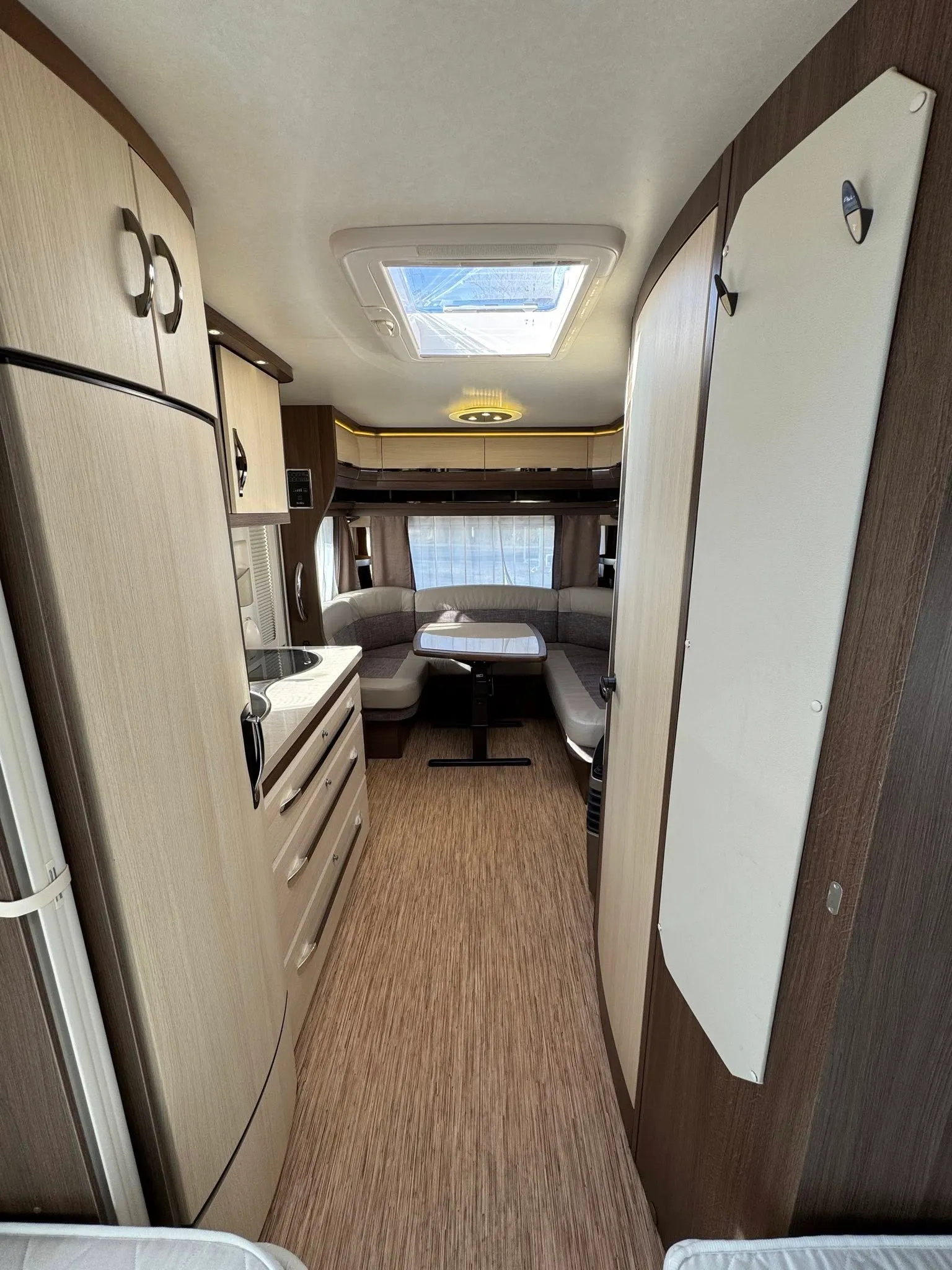 Interiér moderního karavanu se stylovým nábytkem a dostatkem prostoru pro pohodlné sezení.