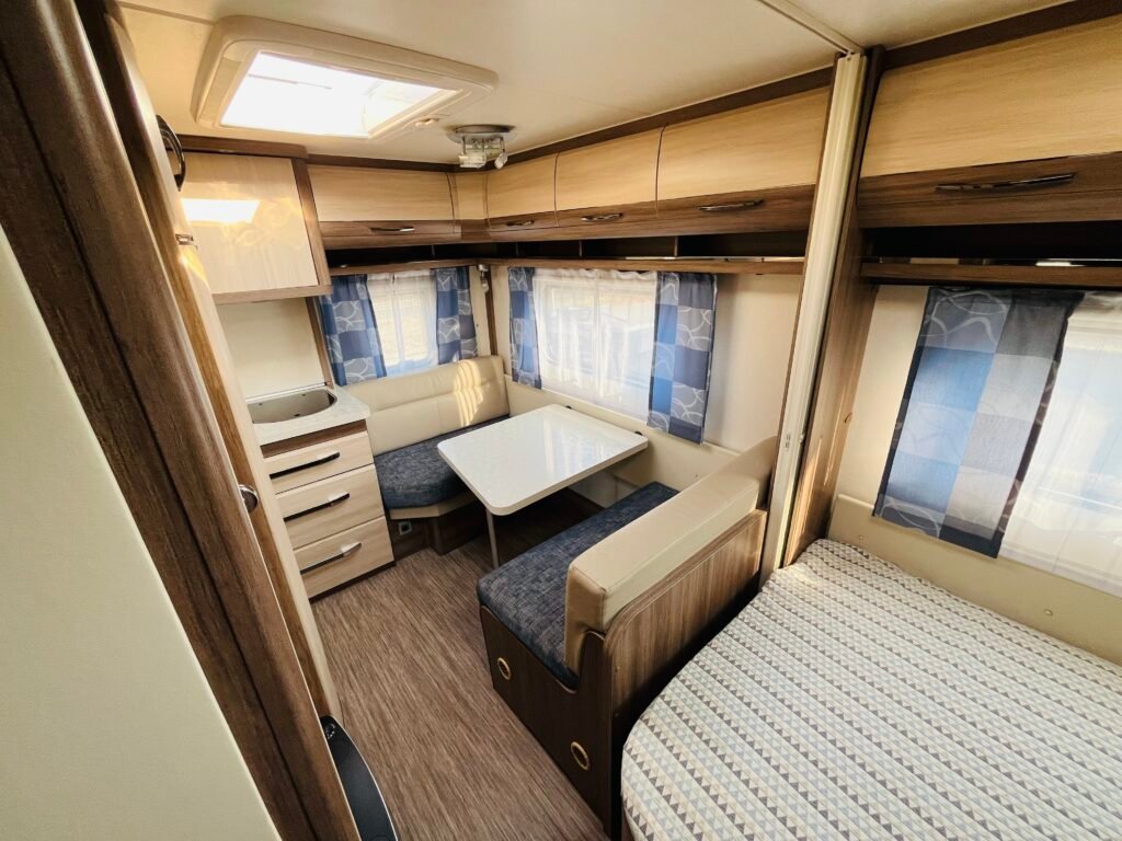 Interiér karavanu s útulným posezením a kuchyňkou. Ideální pro pohodlné cestování a dovolenou.