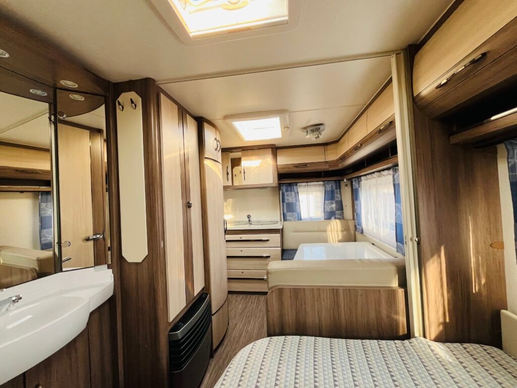 Interiér karavanu s dřevěnými obklady a prostorným uspořádáním. Ideální pro pohodlné cestování a odpočinek.