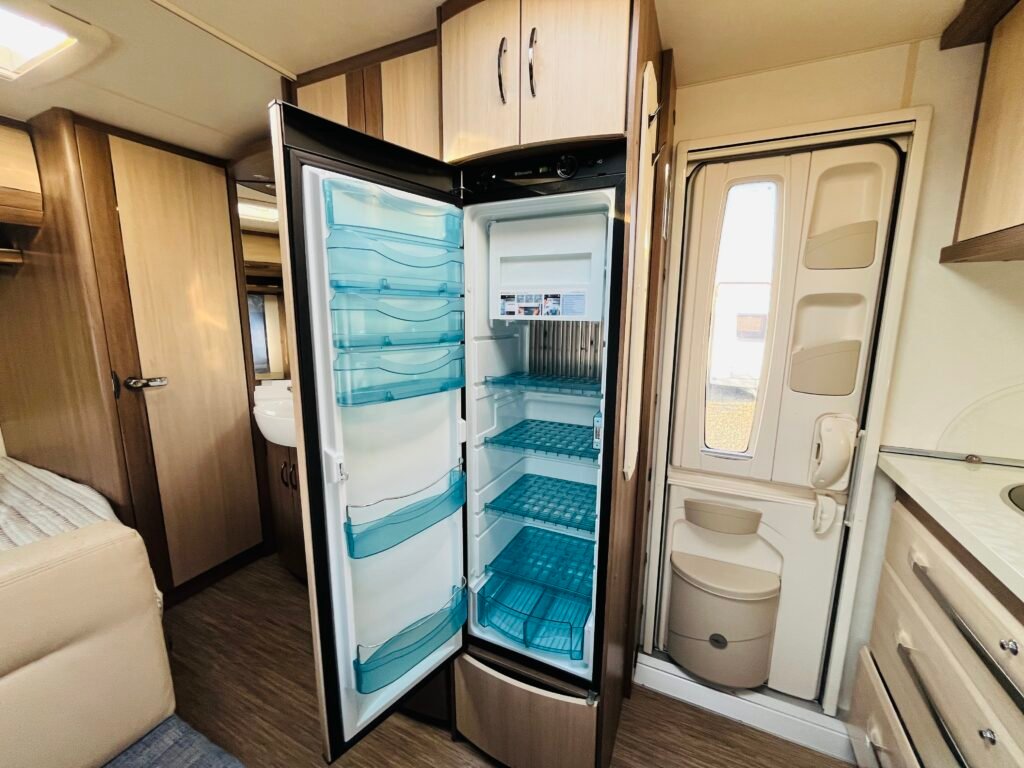Moderní interiér obytného auta, včetně chladničky a koupelny, nabízí pohodlí na cestách.