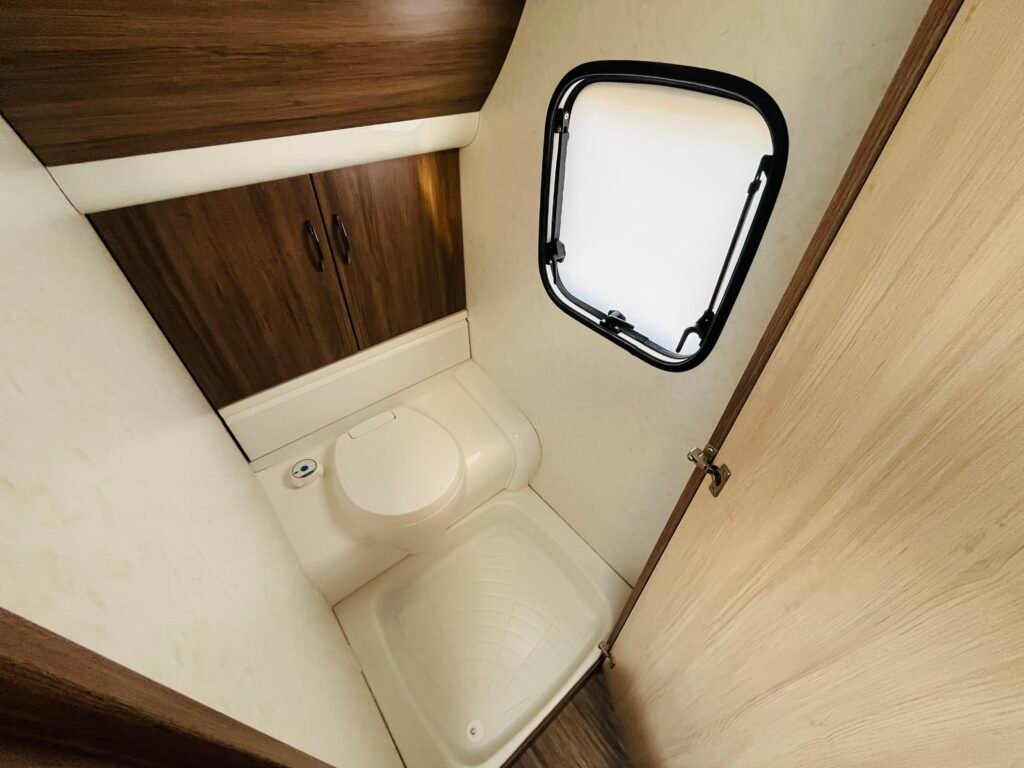 Obrázek zobrazuje koupelnu v karavanu, moderní design s toaletou a skříňkami pro úložný prostor.