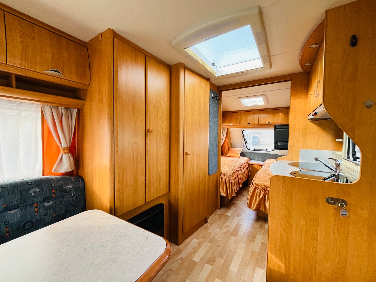 Stylový karavan s dřevěným interiérem a dvoulůžkovým uspořádáním, ideální pro pohodlné cestování.