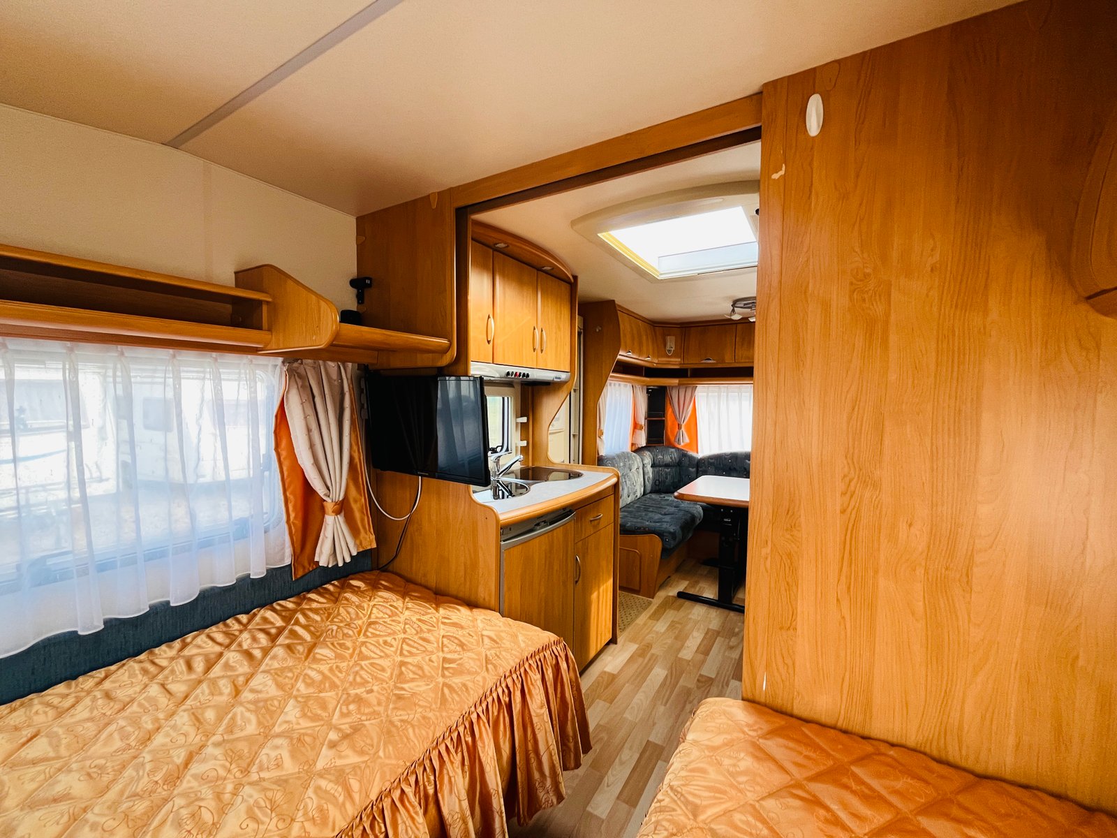 Interiér karavanu s pohodlným uspořádáním, kuchyňským koutem a obývací částí. Ideální pro cestování a odpočinek.