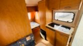 Interiér karavanu s kuchyňským koutem a lůžkem. Ideální pro pohodlné cestování a odpočinek.