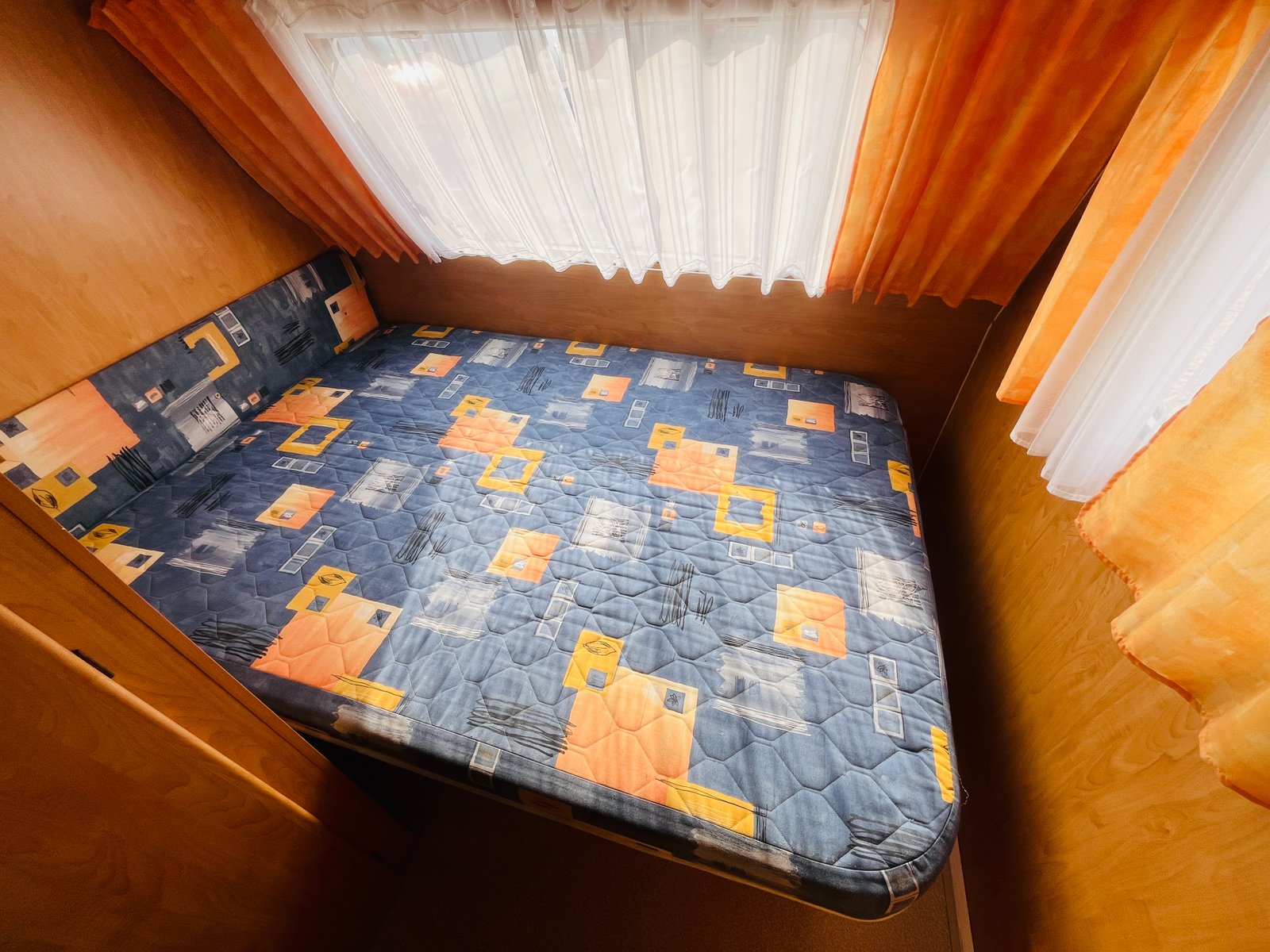 Obrázek ložnice v karavanu s barevným matrací. Příjemné prostředí pro odpočinek.