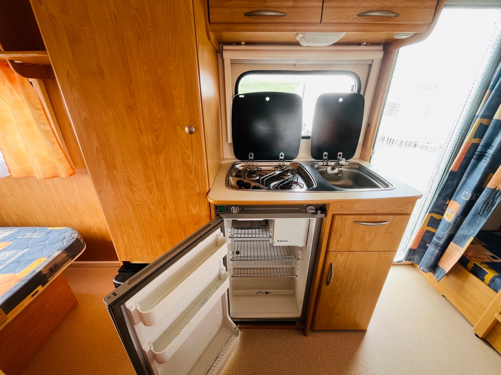 Kuchyňský kout v karavanu s chladničkou, sporákem a dřezem. Ideální pro cestování a kempování.