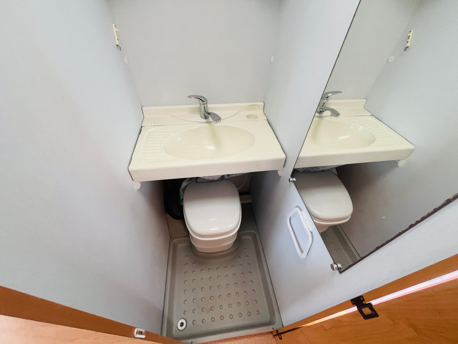 Obrázek interiéru v obytném voze s umyvadlem a toaletou. Kombinace pohodlí a funkčnosti pro cestování.