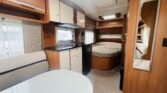 Interiér karavanu s kuchyňským koutem a manželskou postelí, pohodlný a praktický. Ideální pro cestování.