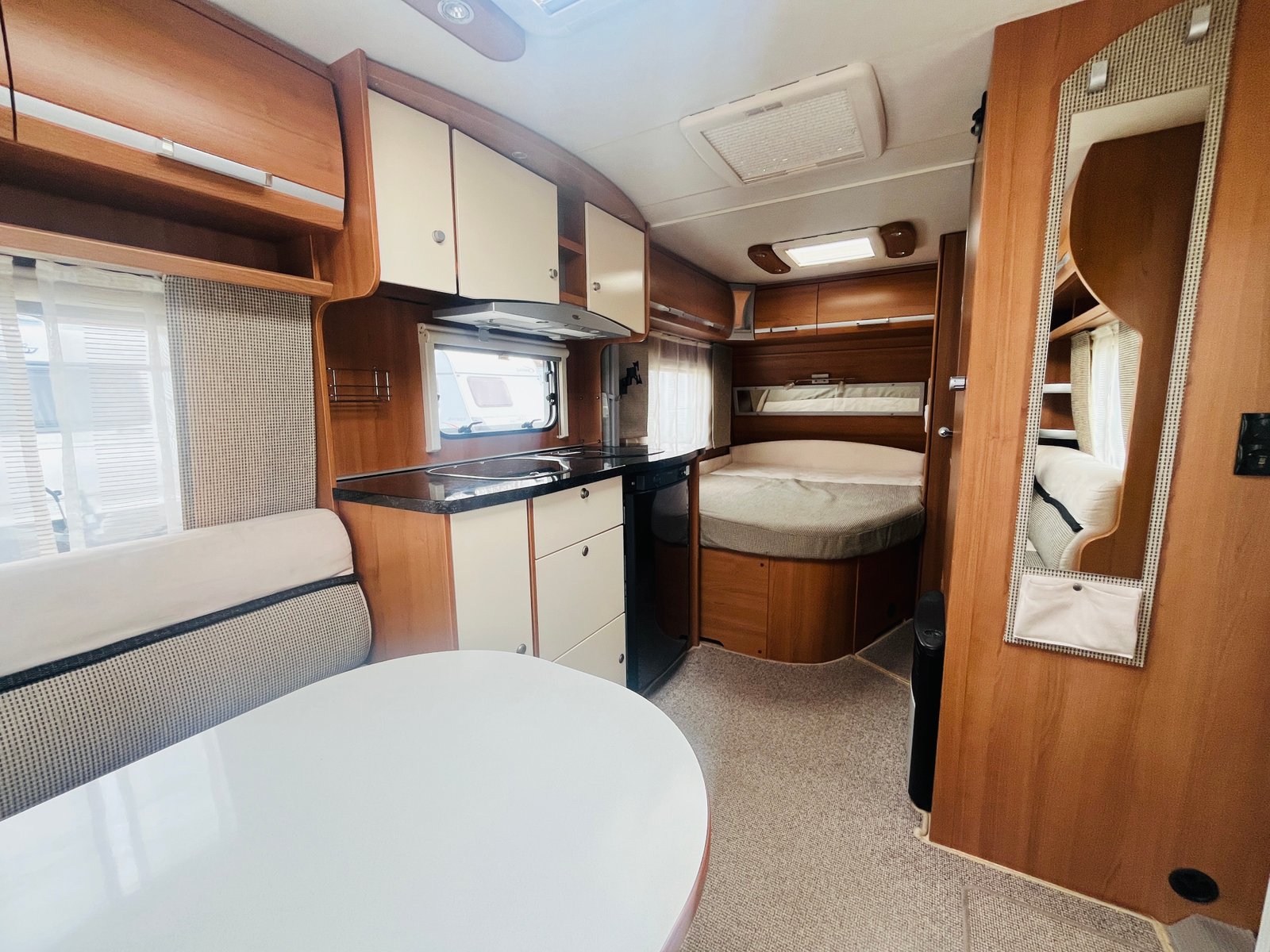 Interiér karavanu s kuchyňským koutem a manželskou postelí, pohodlný a praktický. Ideální pro cestování.