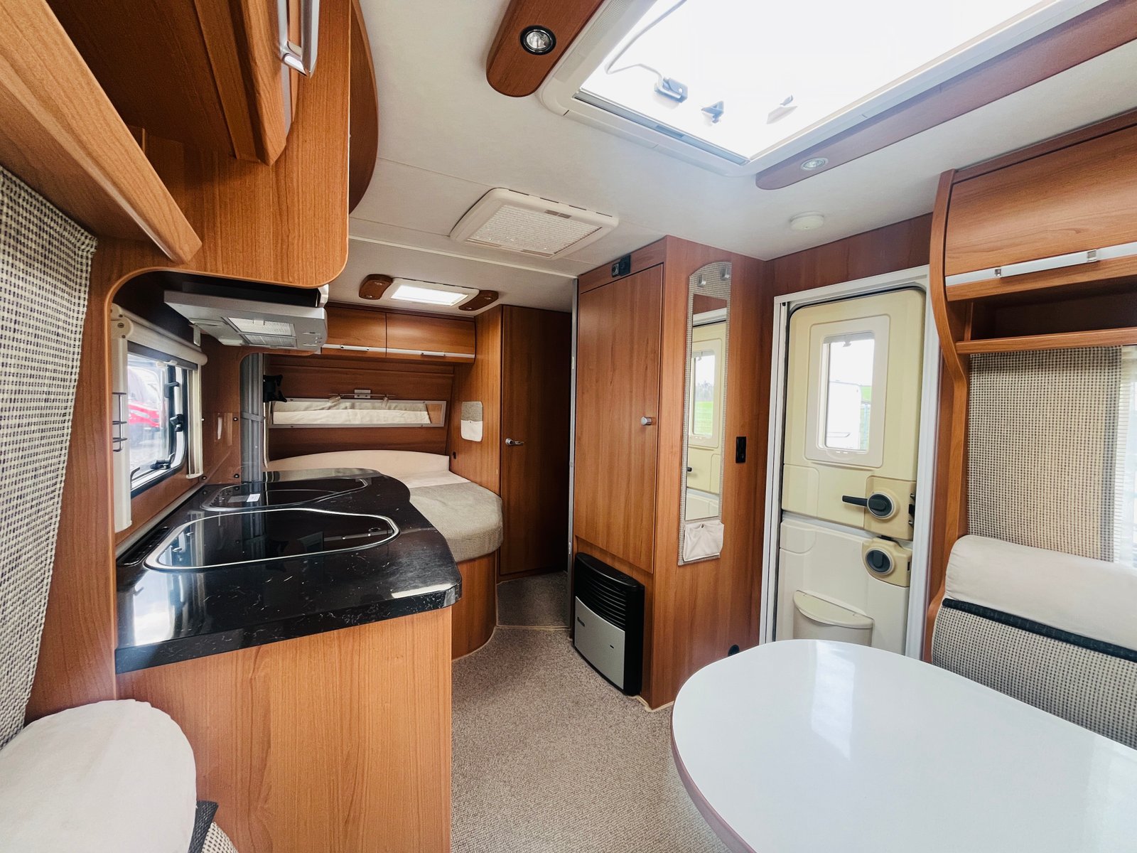 Obrázek interiéru obytného auta s elegantním dřevěným designem a moderním vybavením.