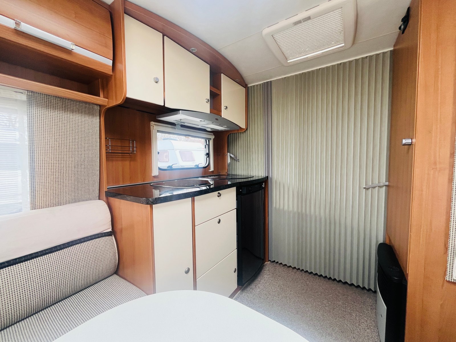 Interiér karavanu s kuchyňským koutem, jídelním stolem a pohodlným sezením. Ideální pro kempování a dobrodružství.
