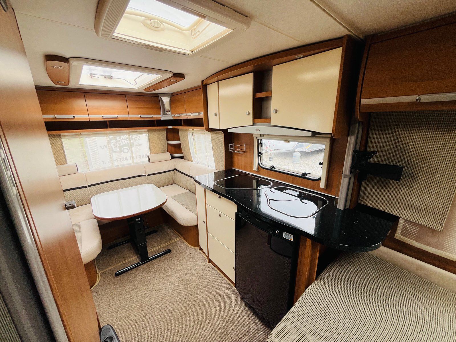 Interiér obytného auta s kuchyňským koutem a prostorným posezením. Moderní a útulný design.