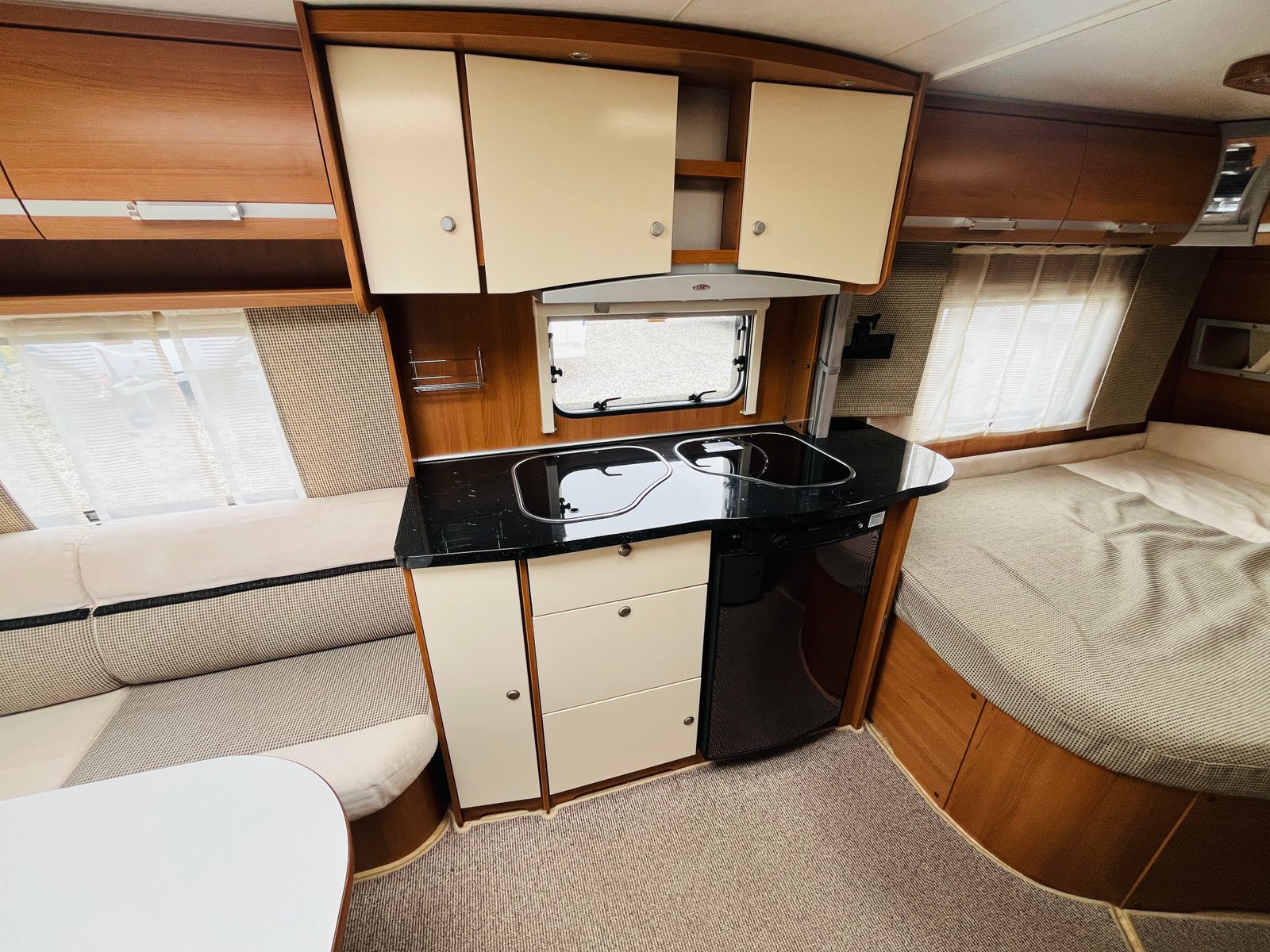 Interiér karavanu s kuchyňským koutem a gaučem, vyrobený z příjemných materiálů. Komfortní a praktický prostor.